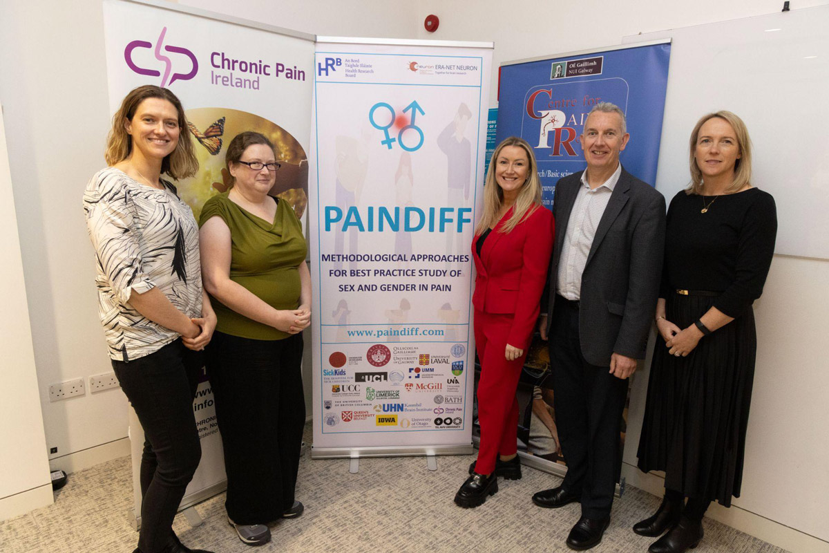 Group of five adults standing beside a vertical PAINDIFF project banner in an indoor setting